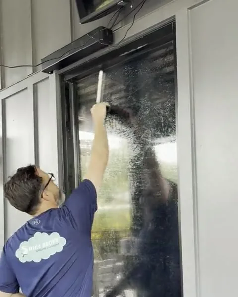 Nick soaping and washing a tall window, a frame from his work video